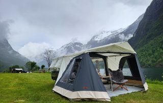 Combi-Camp Country Faltcaravan aufgebaut auf einer Wiese mit Bergen im Hintergrund.